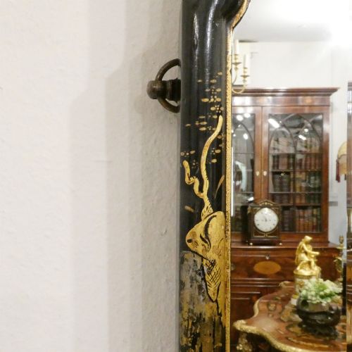 fig 2. An arched wall mirror with a dark lacquered frame featuring gilded Chinoiserie motifs and segmented glass plates.