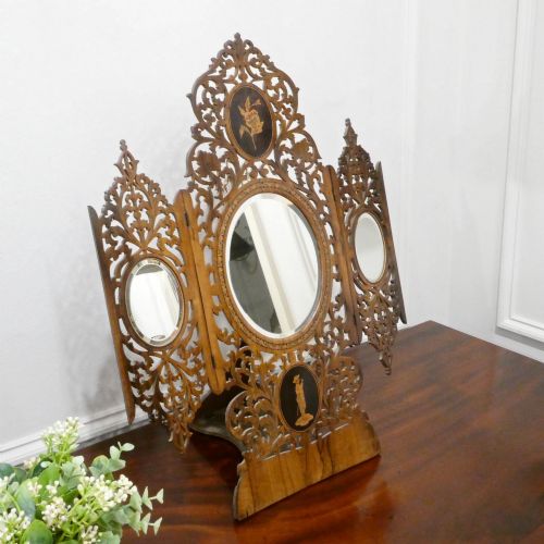fig 1. A fretted walnut triptych dressing table mirror featuring central oval glass plates surrounded by openwork carved scroll patterns and inlaid timber panels.