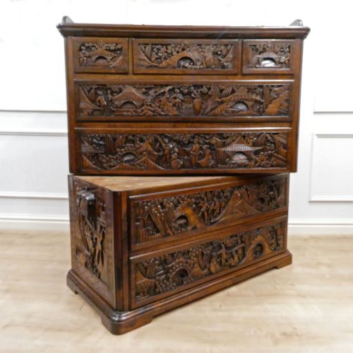 fig 1. A tall early twentieth-century camphor wood chest of drawers featuring elaborate relief-carved oriental landscapes on the drawer fronts and side panels.