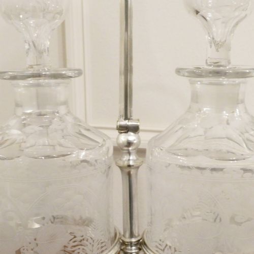 fig 1. A Victorian silver-plated decanter stand with a central arched handle holding three etched glass decanters with stoppers.