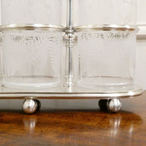 fig 3. A Victorian silver-plated decanter stand with a central arched handle holding three etched glass decanters with stoppers.