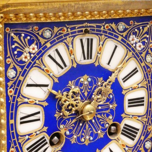fig 2. A French gilt bronze mantel clock featuring two cherub figures atop an ornate golden structure with cobalt blue porcelain panels and Roman numerals.