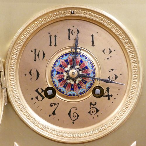 fig 1. A nineteenth-century French gilt brass mantel clock featuring colourful champleve enamel geometric patterns, flanked by two matching decorative urns.