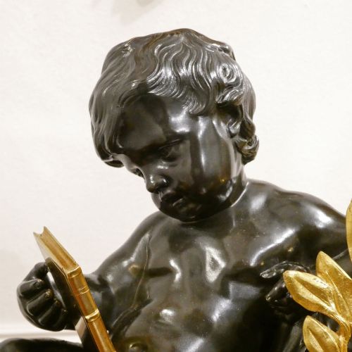 fig 2. A 19th-century French gilt bronze mantel clock featuring a dark patinated bronze cherub seated beside a circular enamel dial atop a gilt relief base.