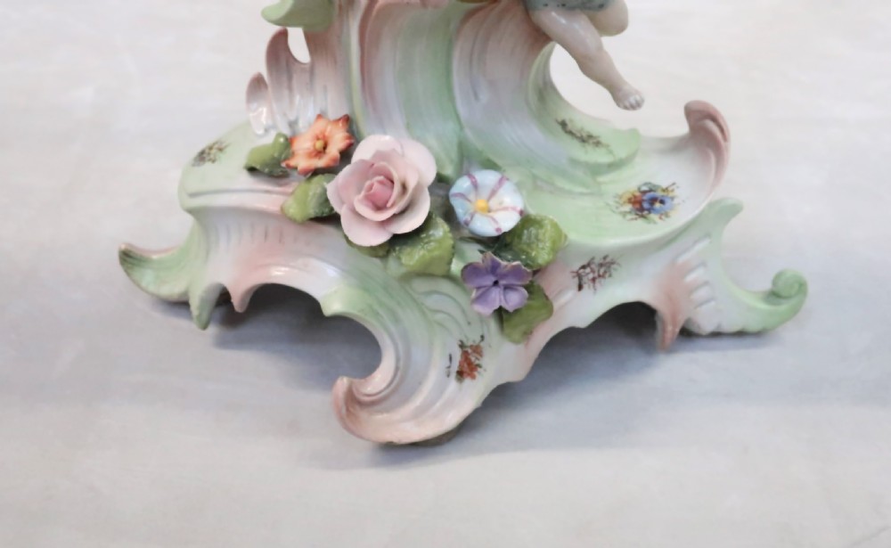 A pair of elaborate multi-branch porcelain candelabra adorned with applied flowers, Rococo scrollwork, and figurative sculptures in pastel shades. View V
