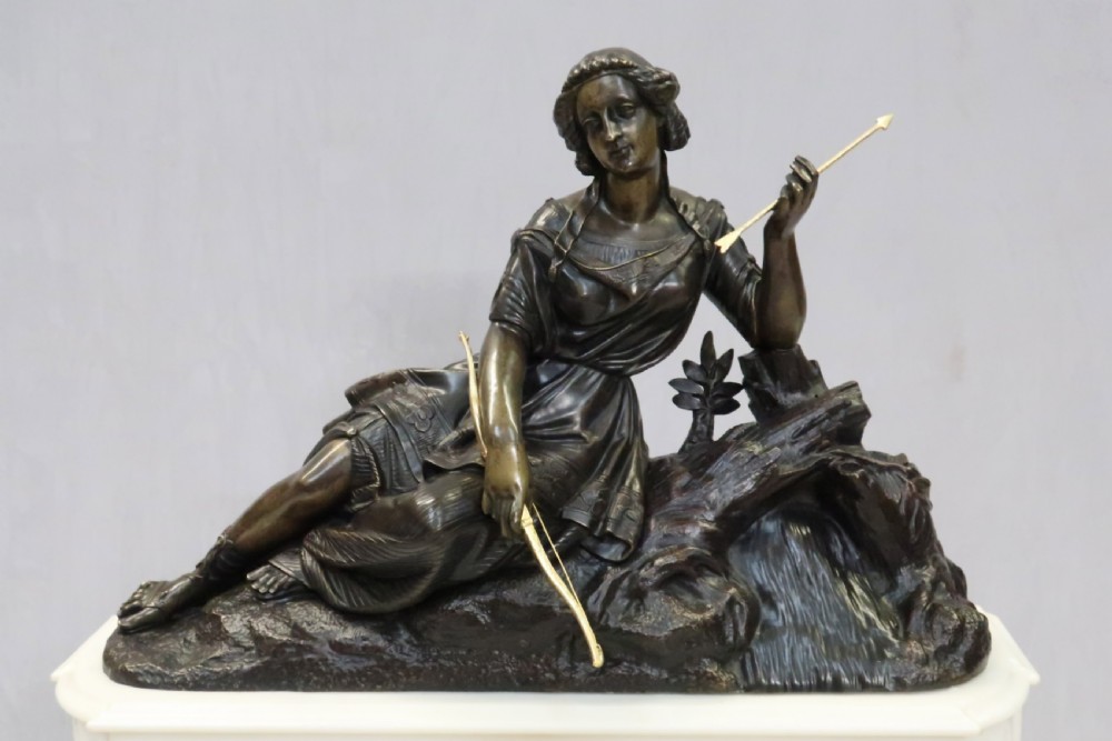 An antique French Napoleon III mantel clock featuring a dark patinated bronze figure of Diana the Huntress holding a bow, set atop a rectangular white marble base with gilt-bronze mounts. View IV