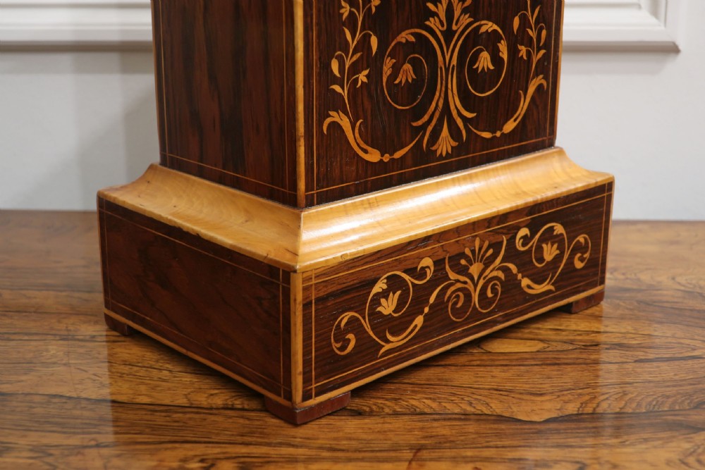 A nineteenth-century rectangular dark rosewood mantel clock featuring foliate marquetry inlay, a brass-rimmed circular dial with Roman numerals, and a stepped plinth base. View V