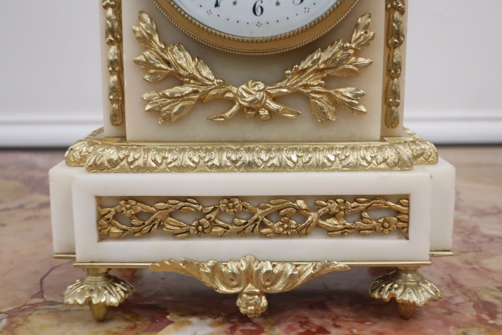 A French Louis XVI style clock garniture set made from white marble and gilt bronze, featuring a central mantel clock topped with an urn finial and flanked by two matching two-light candelabra. View IV