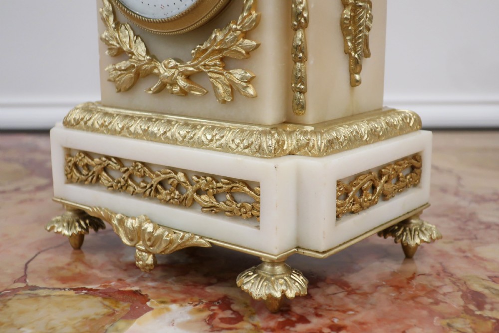 A French Louis XVI style clock garniture set made from white marble and gilt bronze, featuring a central mantel clock topped with an urn finial and flanked by two matching two-light candelabra. View V