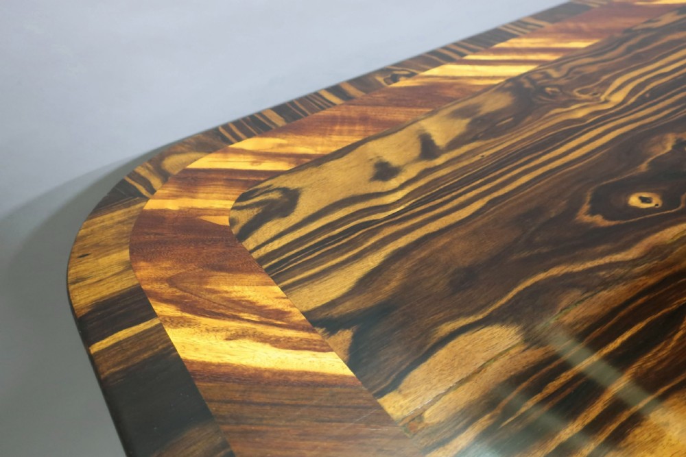 A Regency coromandel wood breakfast table featuring a rectangular top with rounded corners, dark banded grain, and a central column base on a quadform platform. View IV