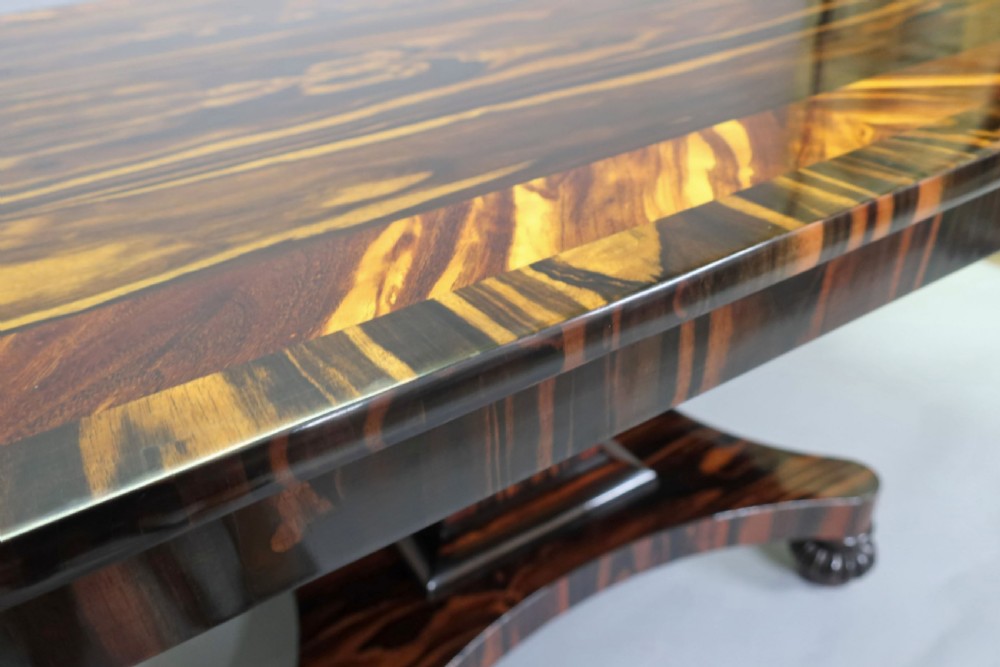 A Regency coromandel wood breakfast table featuring a rectangular top with rounded corners, dark banded grain, and a central column base on a quadform platform. View VI