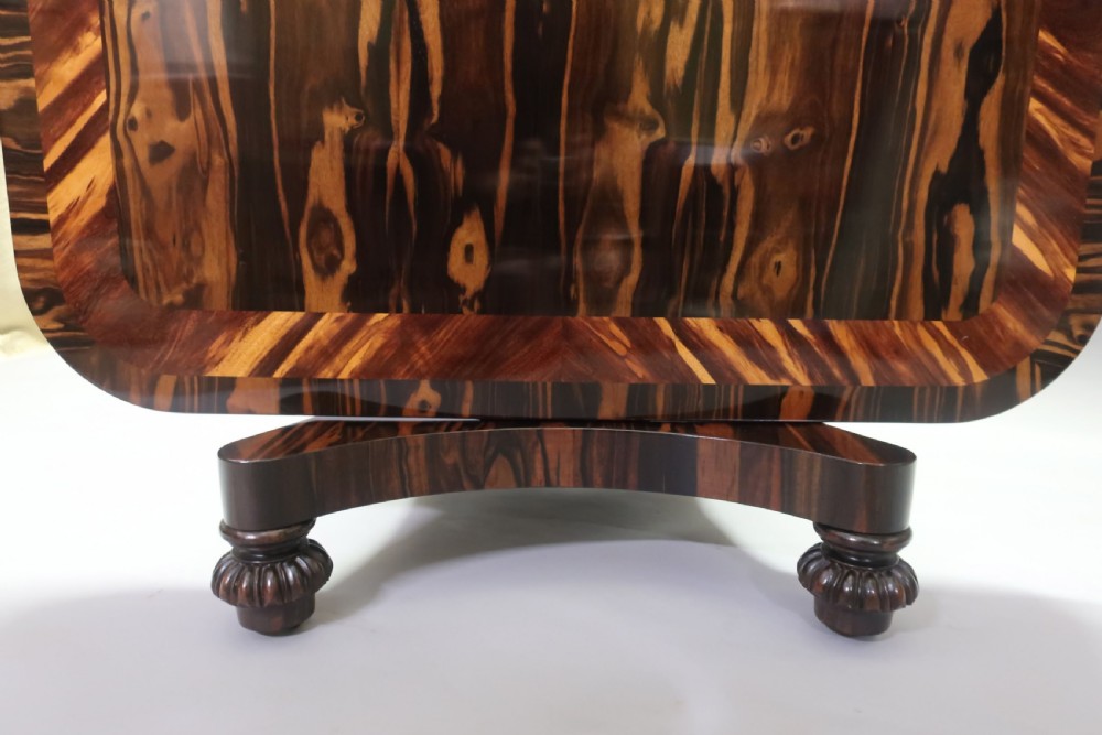 A Regency coromandel wood breakfast table featuring a rectangular top with rounded corners, dark banded grain, and a central column base on a quadform platform. View VIII