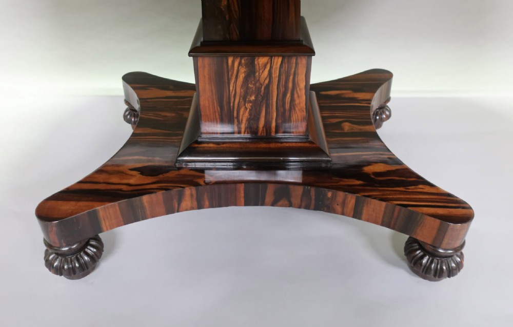 A Regency coromandel wood breakfast table featuring a rectangular top with rounded corners, dark banded grain, and a central column base on a quadform platform. View X