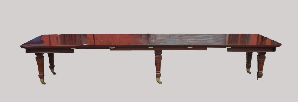 A long Victorian mahogany imperial extending dining table with a polished surface finish, fluted turned legs, and brass castors. View II