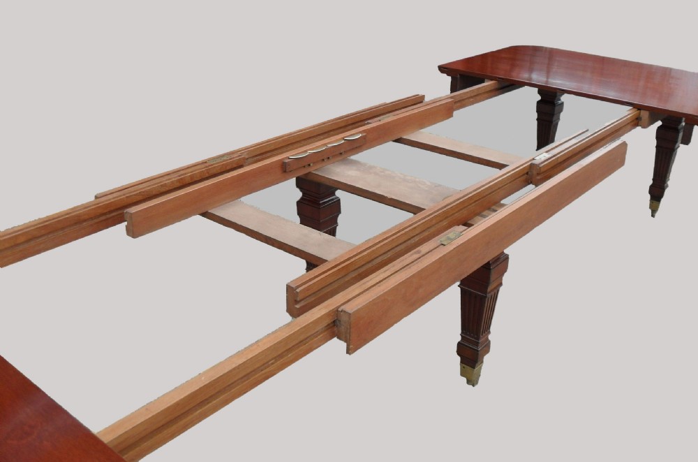 A long Victorian mahogany imperial extending dining table with a polished surface finish, fluted turned legs, and brass castors. View VIII