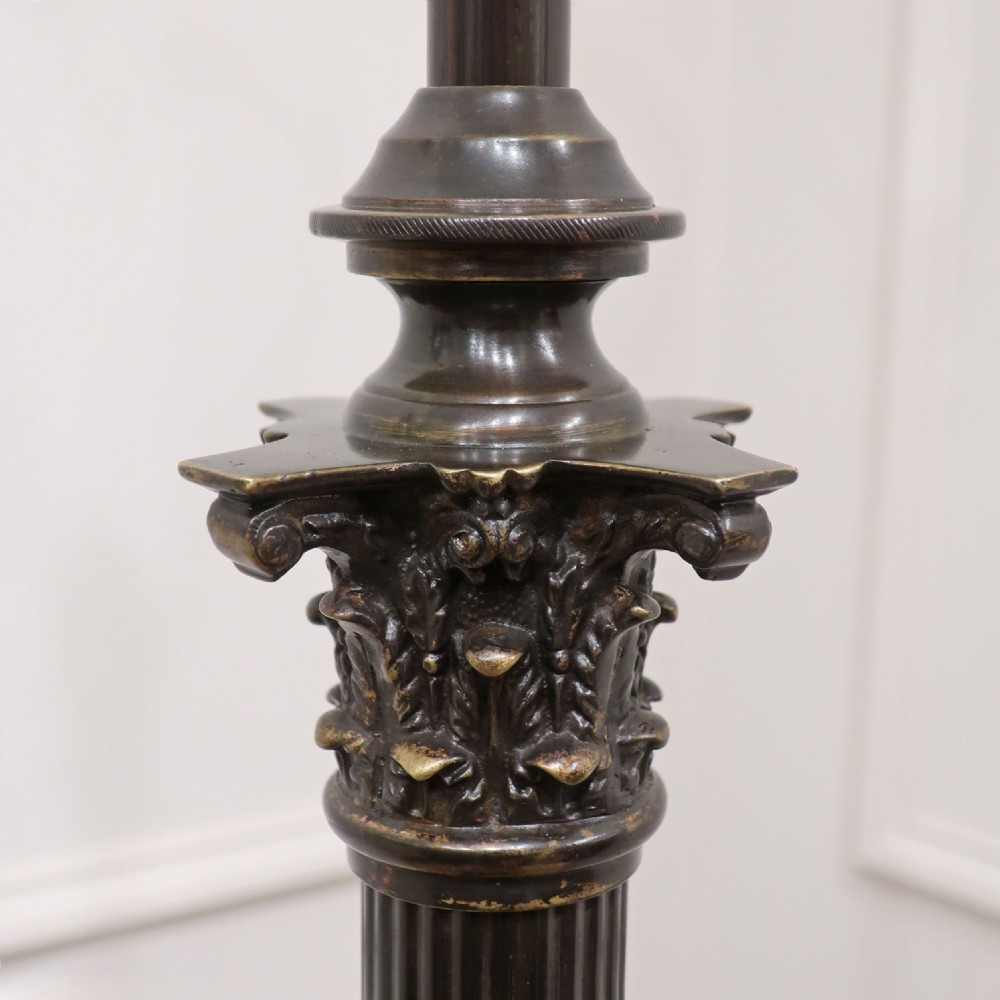 An Edwardian bronzed floor lamp with a pleated cream lampshade, reeded central column, and a stepped square base supported by claw feet. View II