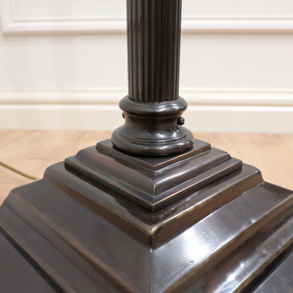 An Edwardian bronzed floor lamp with a pleated cream lampshade, reeded central column, and a stepped square base supported by claw feet. View V