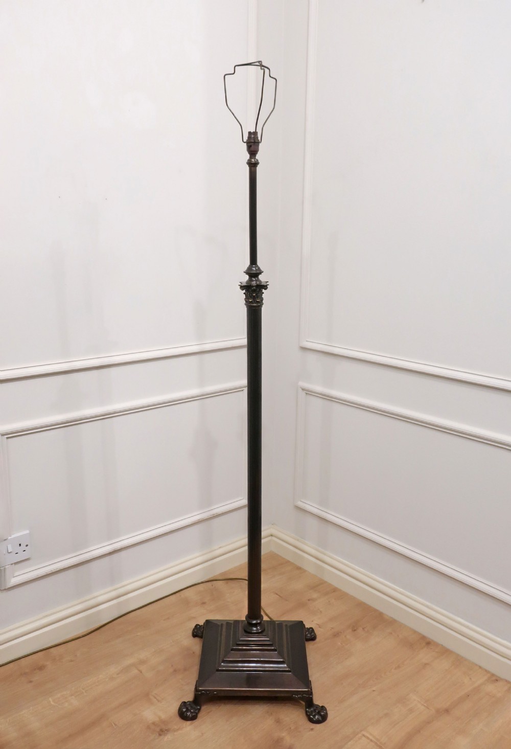 An Edwardian bronzed floor lamp with a pleated cream lampshade, reeded central column, and a stepped square base supported by claw feet. View IX