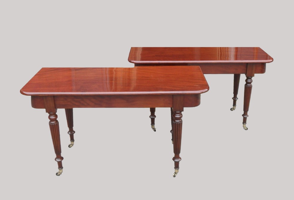 A long Georgian mahogany extending dining table featuring a polished rectangular top with rounded corners supported by reeded legs on brass castors. View VII