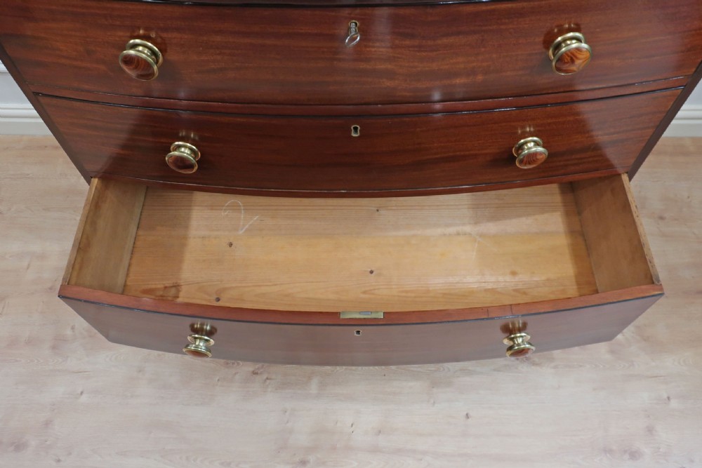 A Georgian bow-fronted mahogany chest of drawers featuring three graduated drawers with circular brass knob handles and splayed bracket feet. View XIII