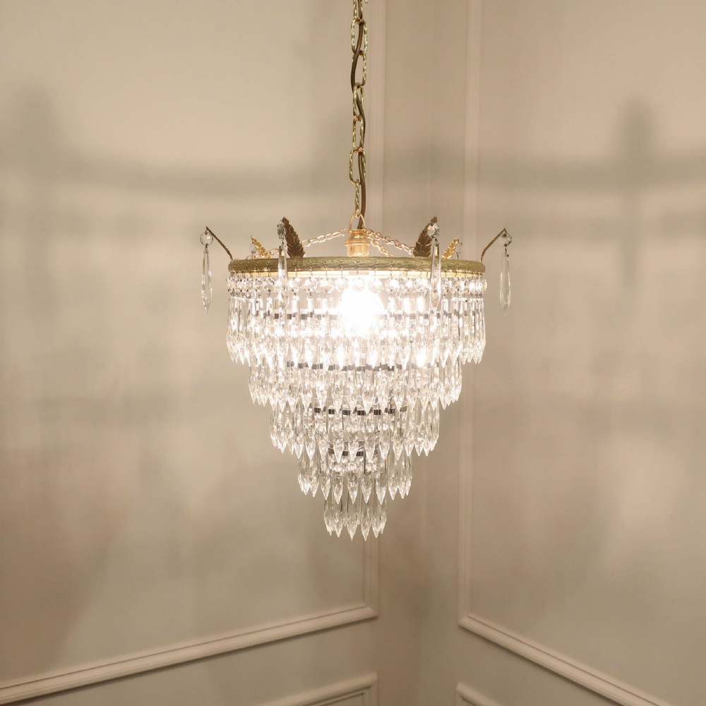 A five-tiered Art Deco chandelier featuring concentric rings of clear glass droplets suspended from a decorative gilt brass rim with a hanging chain. View II
