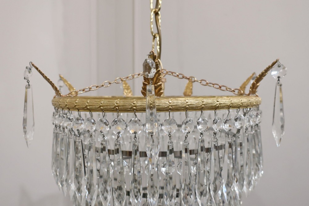 A five-tiered Art Deco chandelier featuring concentric rings of clear glass droplets suspended from a decorative gilt brass rim with a hanging chain. View III