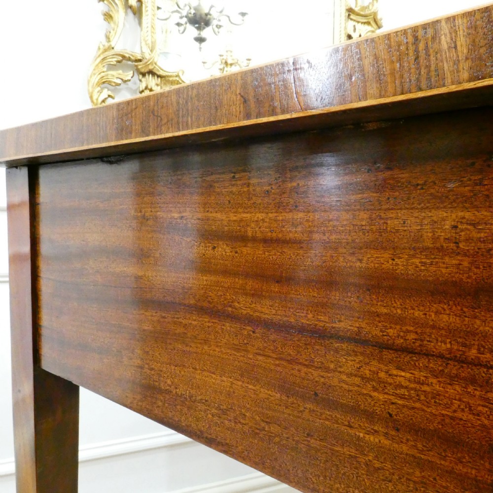 A Georgian mahogany bowfront side table featuring a single drawer with two oval brass handles and square tapered legs. View X