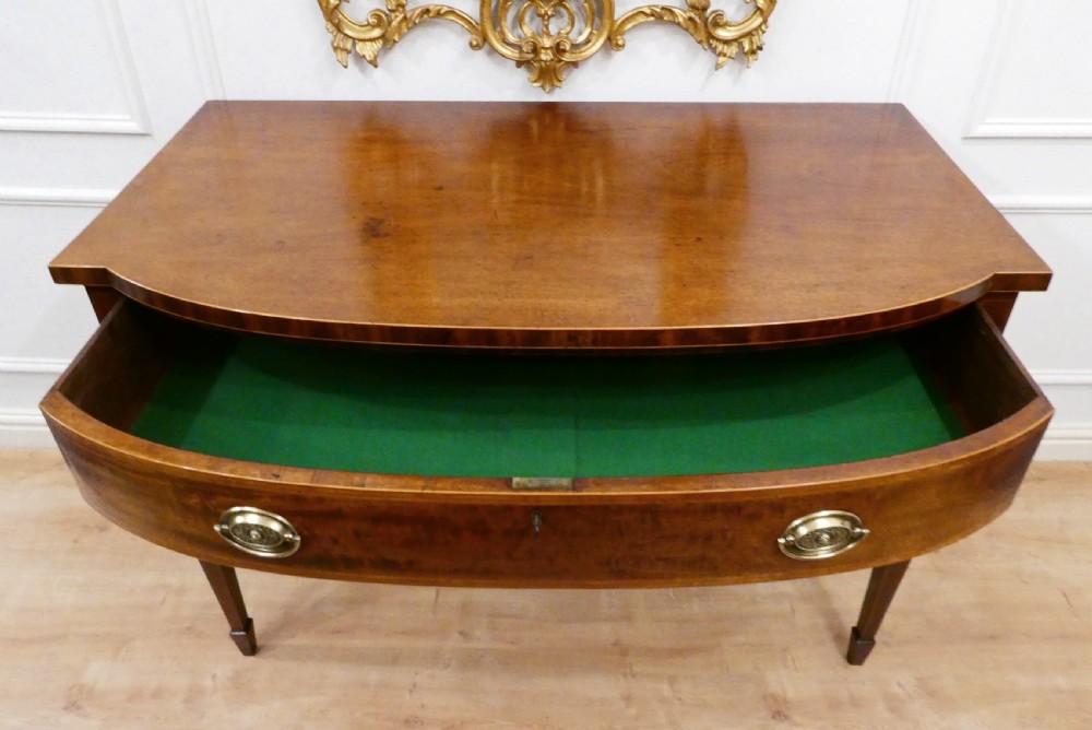 A Georgian mahogany bowfront side table featuring a single drawer with two oval brass handles and square tapered legs. View XV