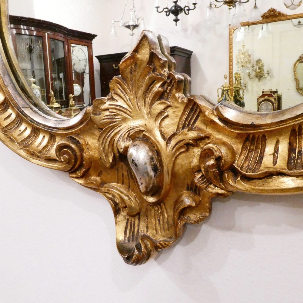 A French Rococo style wall mirror featuring a carved gold leaf frame decorated with acanthus leaf motifs, C-scrolls, and a lattice cartouche crest. View III