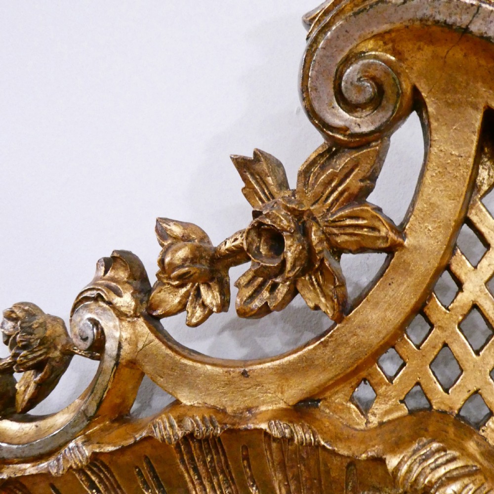 A French Rococo style wall mirror featuring a carved gold leaf frame decorated with acanthus leaf motifs, C-scrolls, and a lattice cartouche crest. View VI