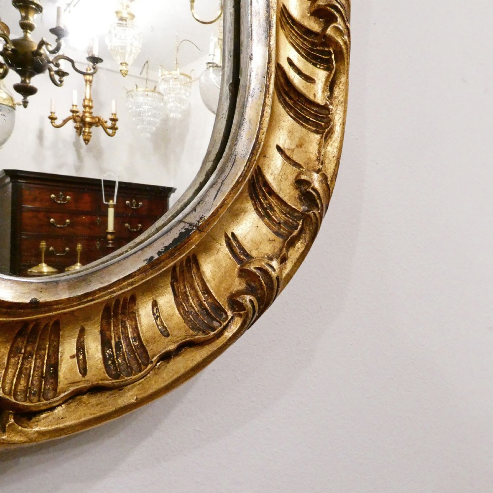 A French Rococo style wall mirror featuring a carved gold leaf frame decorated with acanthus leaf motifs, C-scrolls, and a lattice cartouche crest. View VIII