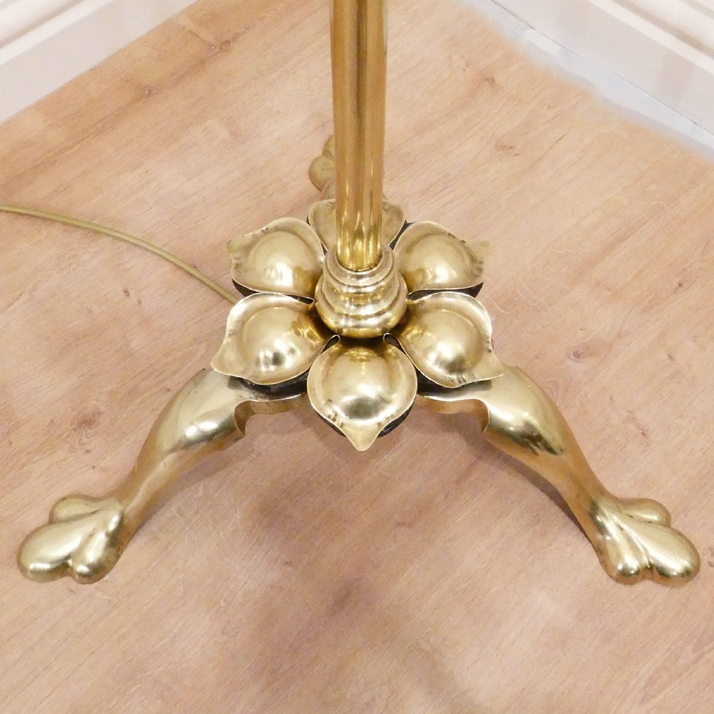 A tall brass standard lamp featuring a tripod base, slender central stem, and a gold fabric dome shade decorated with tassels and fringe. View II