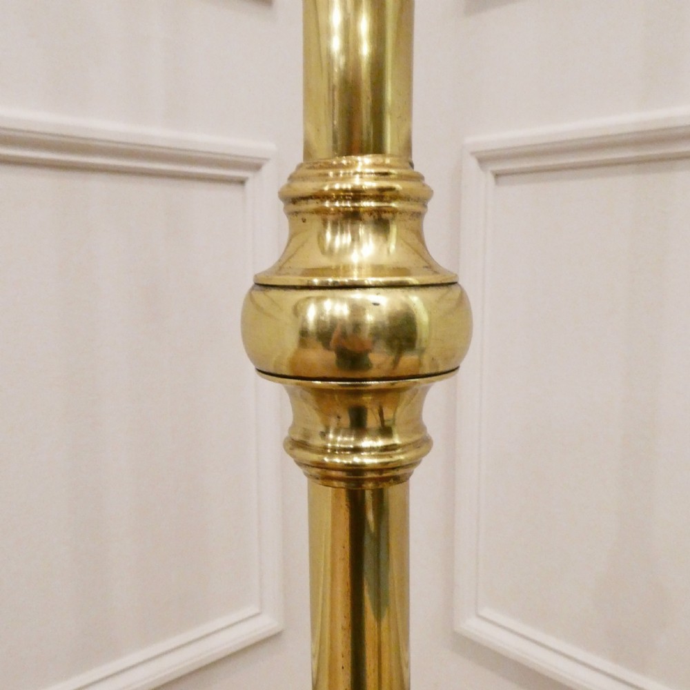 A tall brass standard lamp featuring a tripod base, slender central stem, and a gold fabric dome shade decorated with tassels and fringe. View VIII