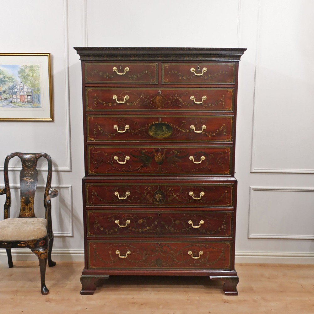 A tall Georgian mahogany chest on chest with hand-painted polychrome panels, brass handles, and bracket feet.