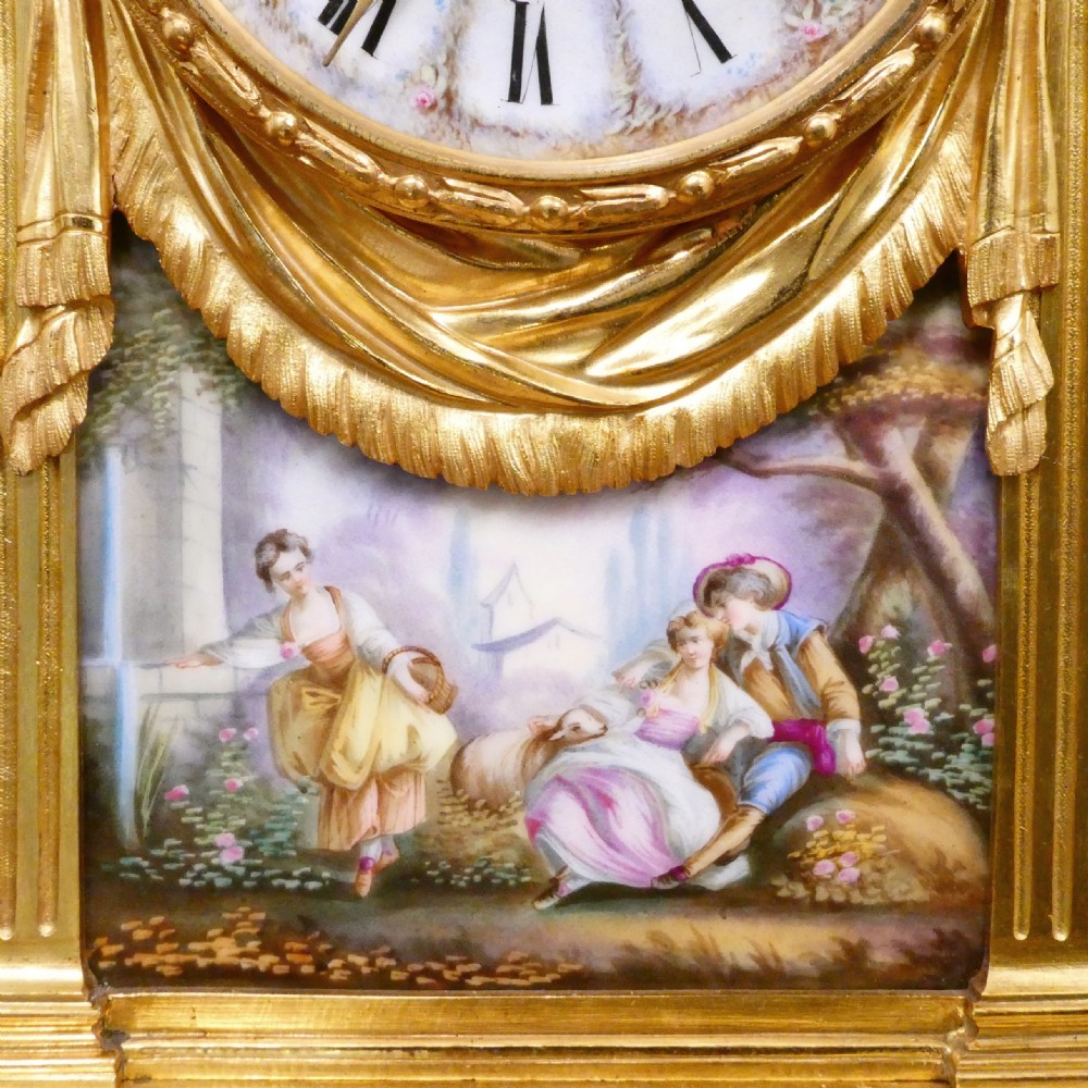 A French Louis XVI style gilt bronze mantel clock featuring a porcelain urn top, hand-painted floral porcelain panels, and Roman numerals on the dial. View IV