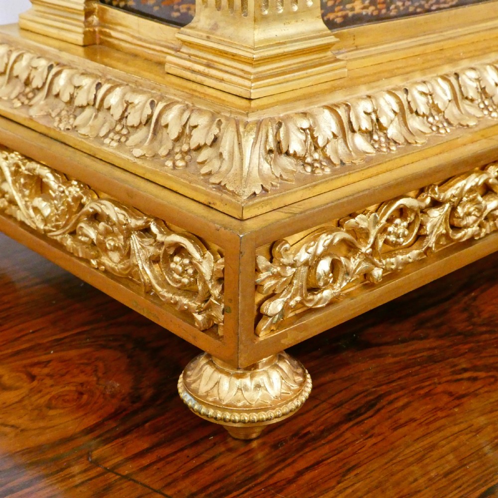 A French Louis XVI style gilt bronze mantel clock featuring a porcelain urn top, hand-painted floral porcelain panels, and Roman numerals on the dial. View VI