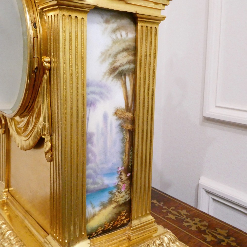 A French Louis XVI style gilt bronze mantel clock featuring a porcelain urn top, hand-painted floral porcelain panels, and Roman numerals on the dial. View XIII