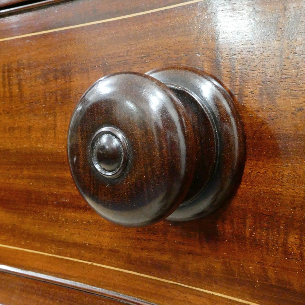 A Georgian mahogany chest of drawers featuring a serpentine front, four graduated drawers with turned wooden knobs, fine line inlay, and bracket feet. View III