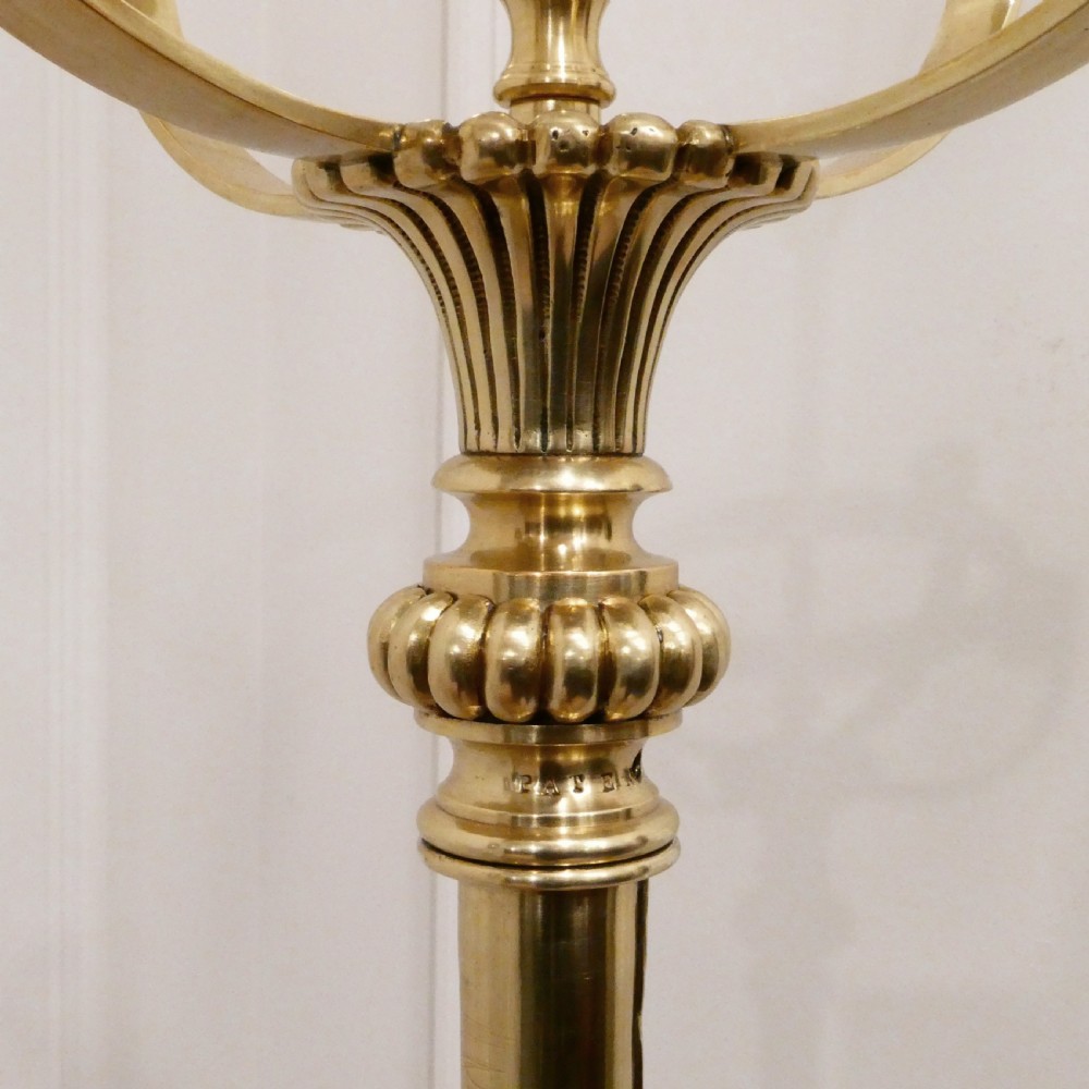 A tall Victorian brass standard lamp featuring a fluted column, tiered square base, and a domed gold silk shade trimmed with beaded fringe and red tassels. View III