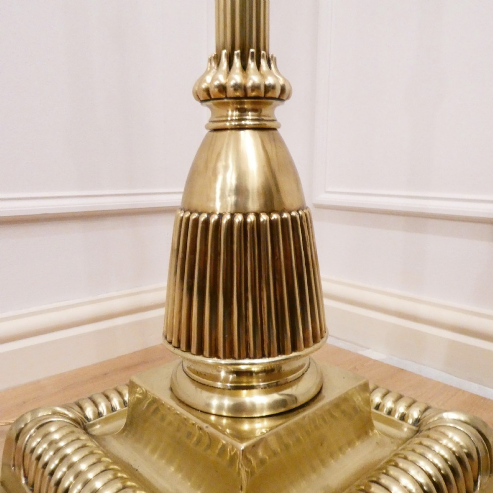 A tall Victorian brass standard lamp featuring a fluted column, tiered square base, and a domed gold silk shade trimmed with beaded fringe and red tassels. View V