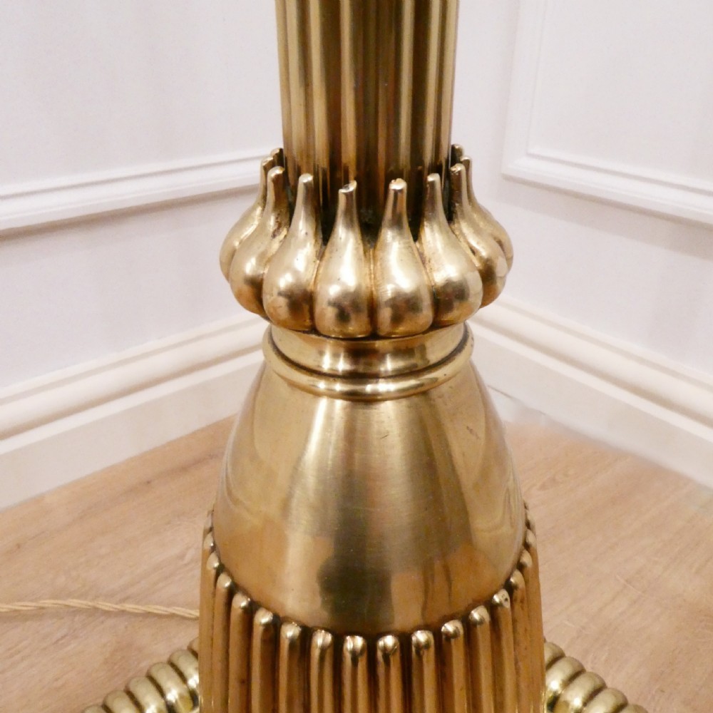 A tall Victorian brass standard lamp featuring a fluted column, tiered square base, and a domed gold silk shade trimmed with beaded fringe and red tassels. View VII