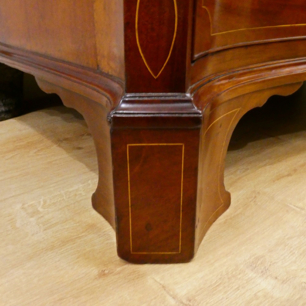 A Georgian mahogany chest of drawers featuring a serpentine front, four graduated drawers with turned wooden knobs, fine line inlay, and bracket feet. View VIII