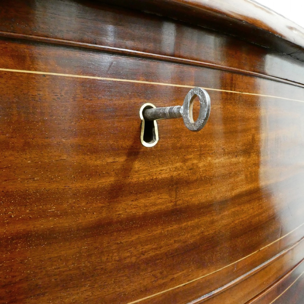 A Georgian mahogany chest of drawers featuring a serpentine front, four graduated drawers with turned wooden knobs, fine line inlay, and bracket feet. View XIV