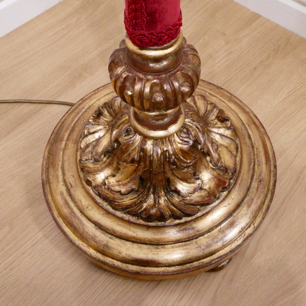 A pair of tall Italian Baroque style giltwood floor lamps featuring red velvet shafts and scalloped fringed shades. View VI