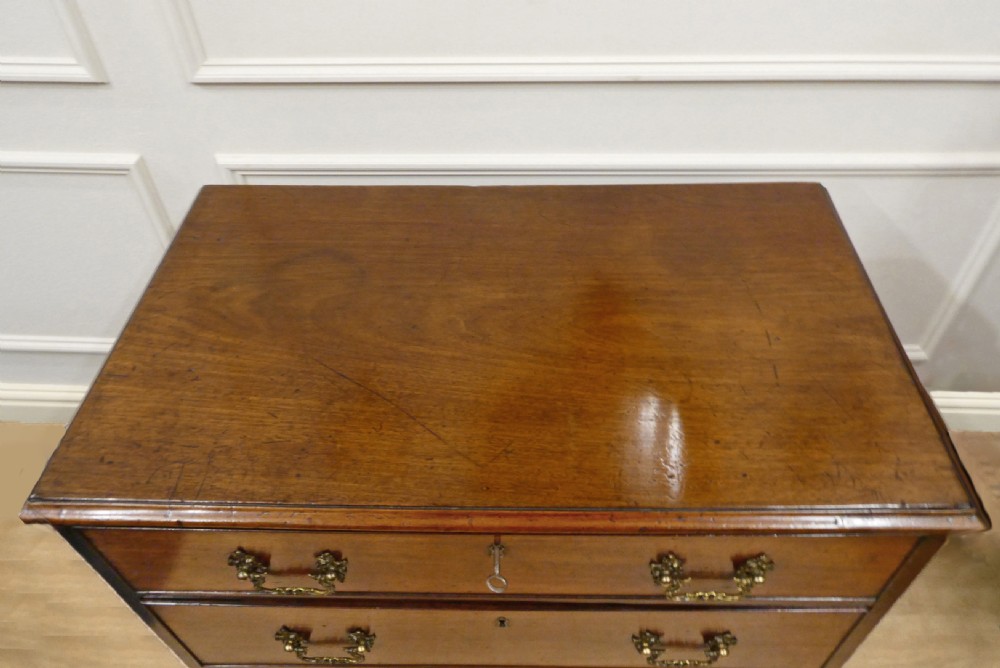 A Georgian Chippendale mahogany chest of drawers with three graduated drawers, decorative brass swan-neck handles, keyhole escutcheons, and ogee bracket feet. View VI