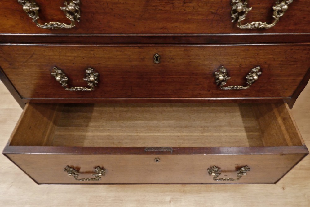 A Georgian Chippendale mahogany chest of drawers with three graduated drawers, decorative brass swan-neck handles, keyhole escutcheons, and ogee bracket feet. View XIII