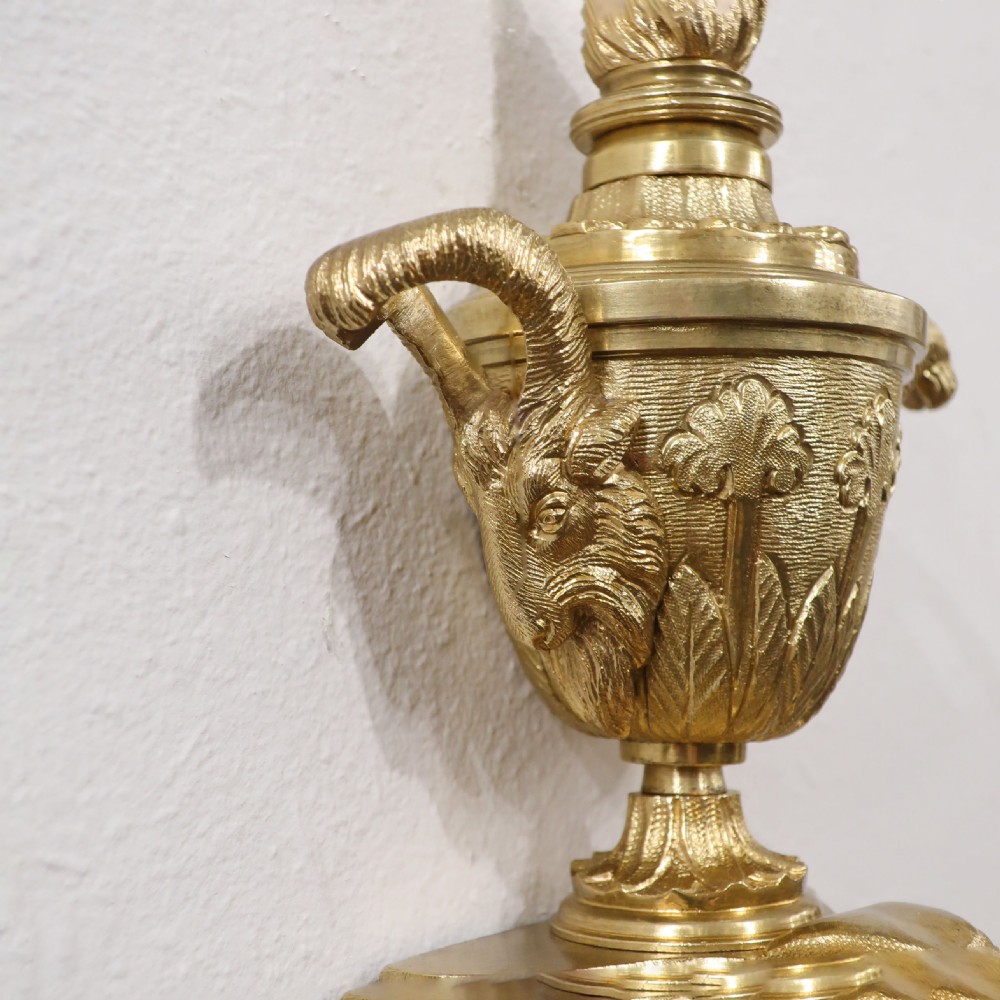 A pair of French gilt bronze twin-arm wall lights featuring classical urn finials and tapered backplates. View IX