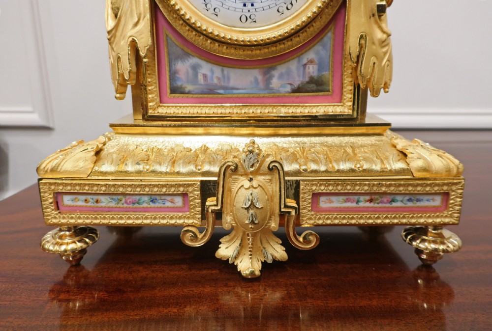 A French gilt bronze mantel clock featuring an urn top finial, pink hand-painted porcelain panels, and a white enamel dial with Roman numerals. View V