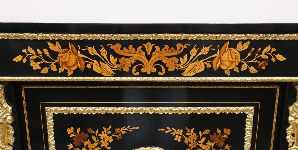 A Victorian ebonised and marquetry credenza side cabinet featuring curved glass display doors, gilt-bronze mounts, and a central floral inlay panel. View VI