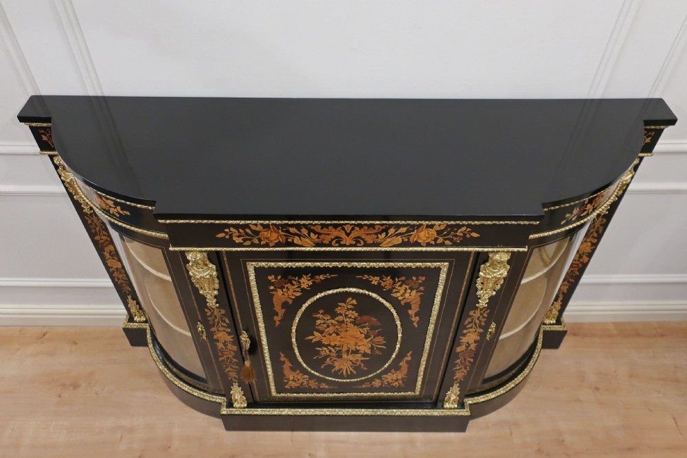 A Victorian ebonised and marquetry credenza side cabinet featuring curved glass display doors, gilt-bronze mounts, and a central floral inlay panel. View X